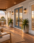Covered front porch at Islabella at sunset, with French doors to the living space, a wood ceiling and seating along the railing.